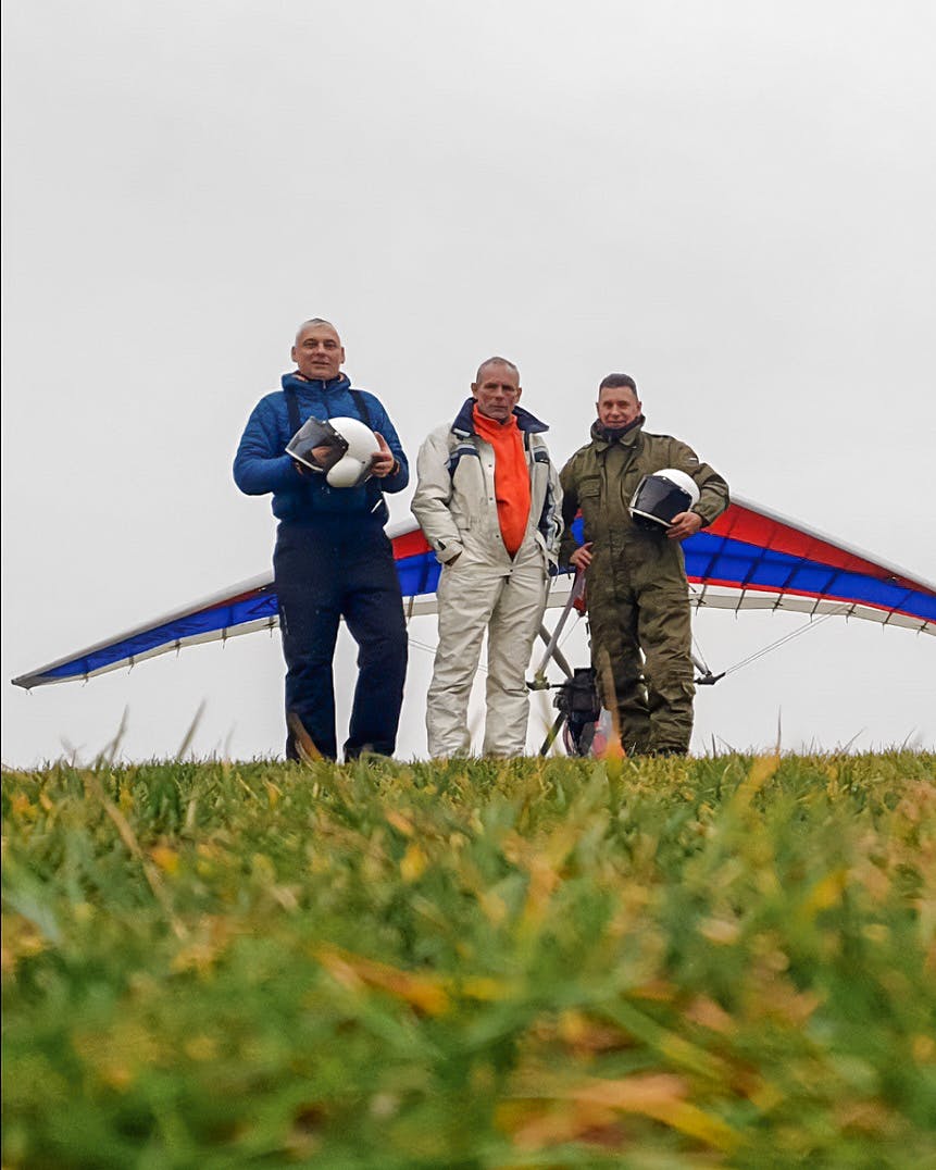 Paweł P., Wojtek M., and Janek C. posing in front of a motor glider.